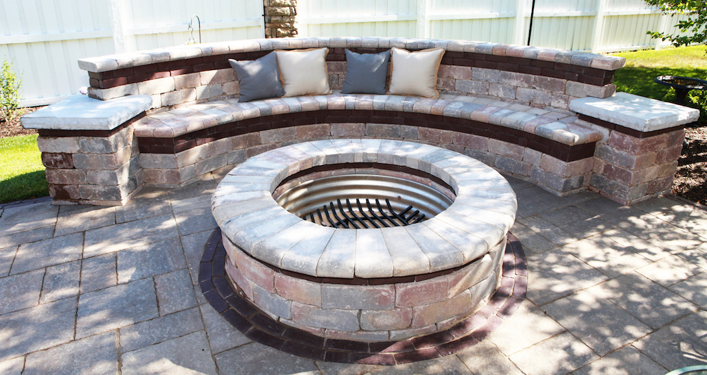 Outdoor stone lounge area with circular brick fire pit | Hittle Landscaping