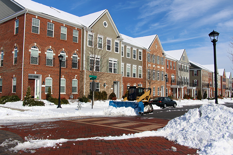 Row of brick and wood townhouse condos along street being plowed of piles of snow | Winter Landscape Tips for Indiana HOA Boards | Hittle Landscape