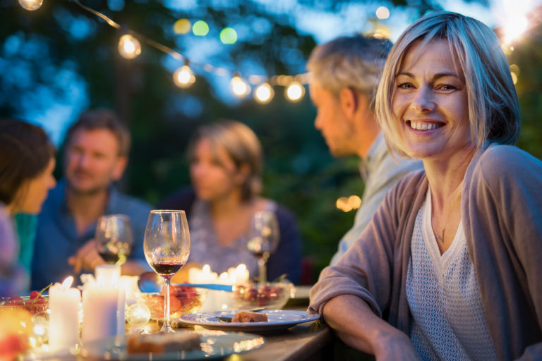 Happy woman at outdoor dinner | Redesign Your Backyard for Outdoor Entertaining | Hittle Landscaping