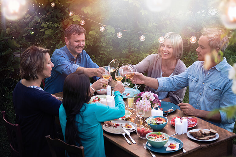 people toasting outdoor dinner | Party Host's Guide to Backyard Landscape Design in Indianapolis | Hittle Landscaping